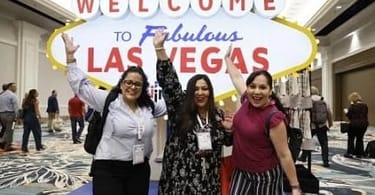 IMEX America attendees pose in front of a Welcome to Las Vegas sign. image courtesy of IMEX